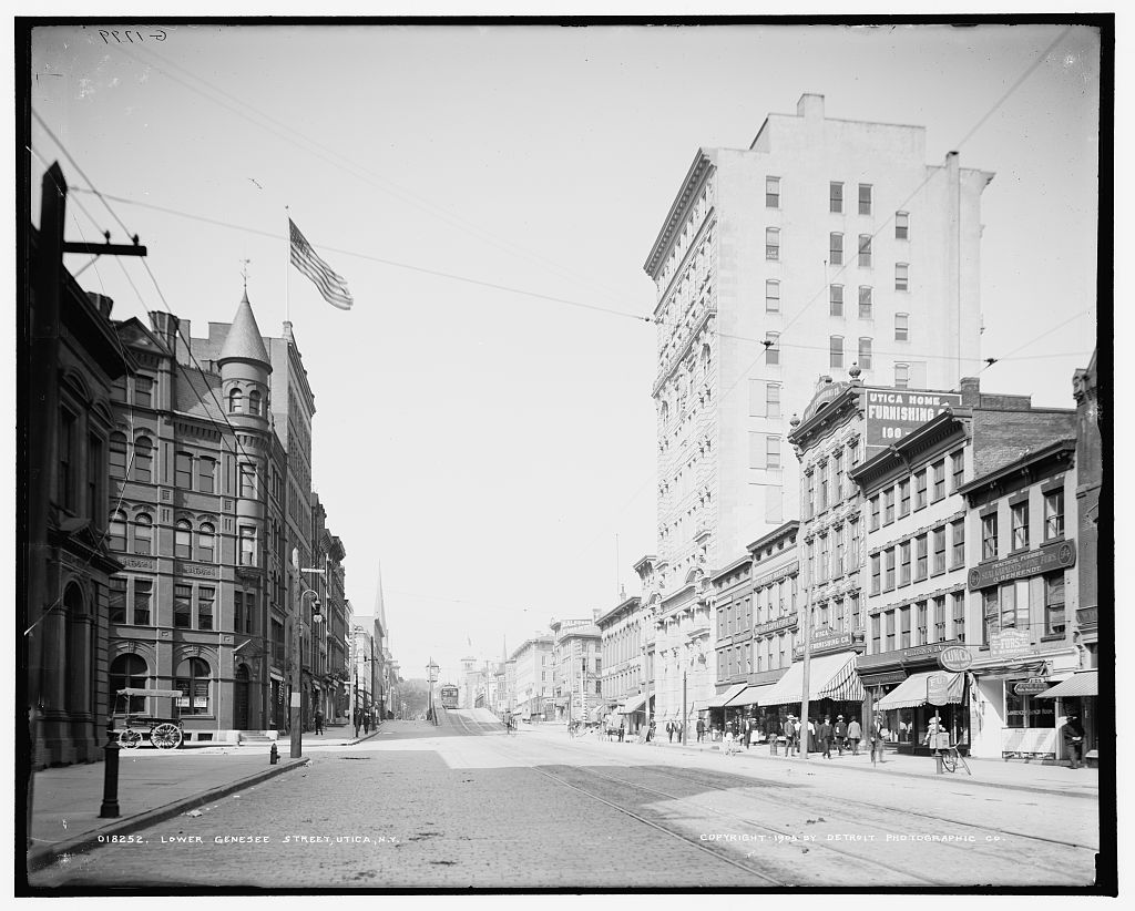 Lower Genesee Street in 1905: cobblestones, streetcar tracks, brick commercial blocks and pedestrians.
