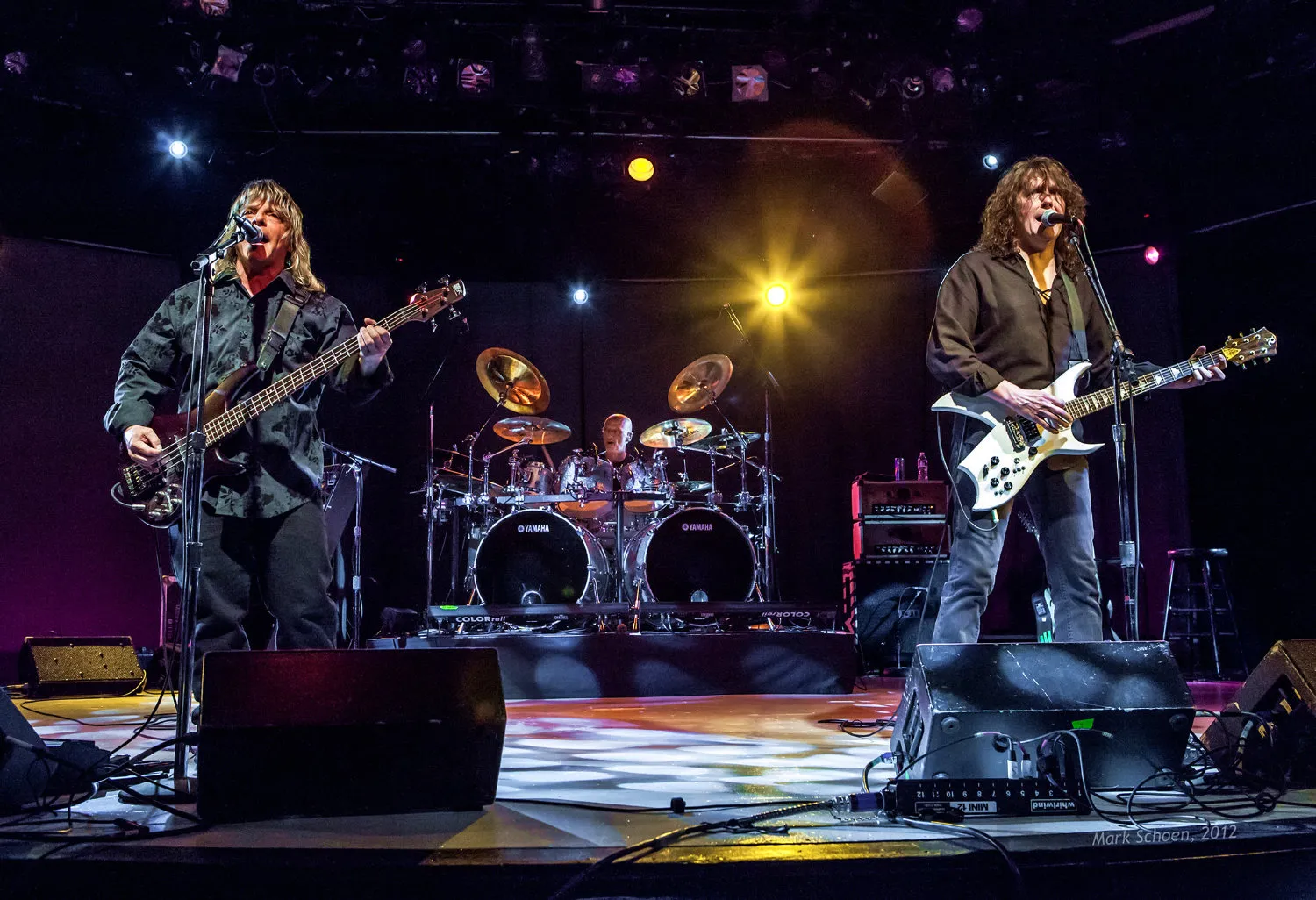 Zebra playing live, two guitarists at the front of the stage with the drummer behind them