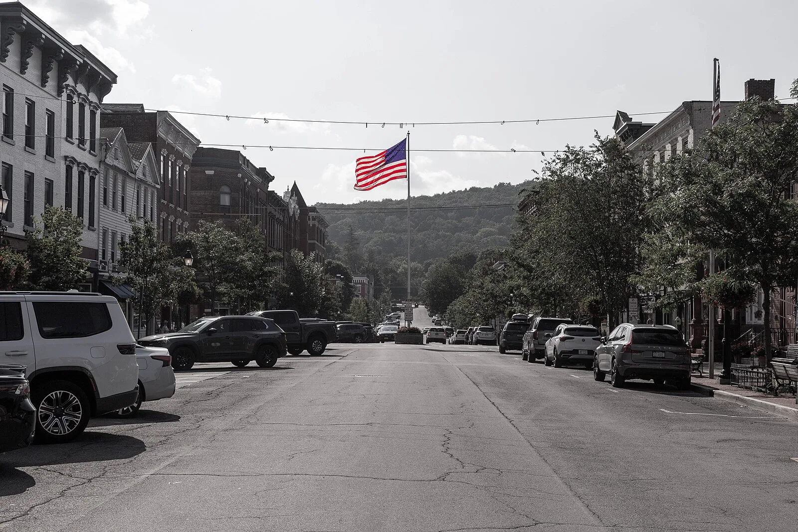 Main Street, Cooperstown, on the Fourth of July, a flag strung over the street and the hills beyond