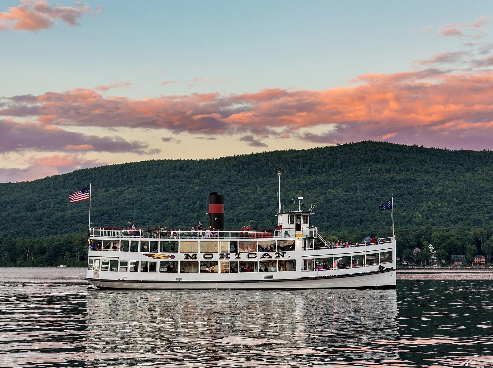The steamboat Mohican II under way on Lake George at dusk, wooded hills behind