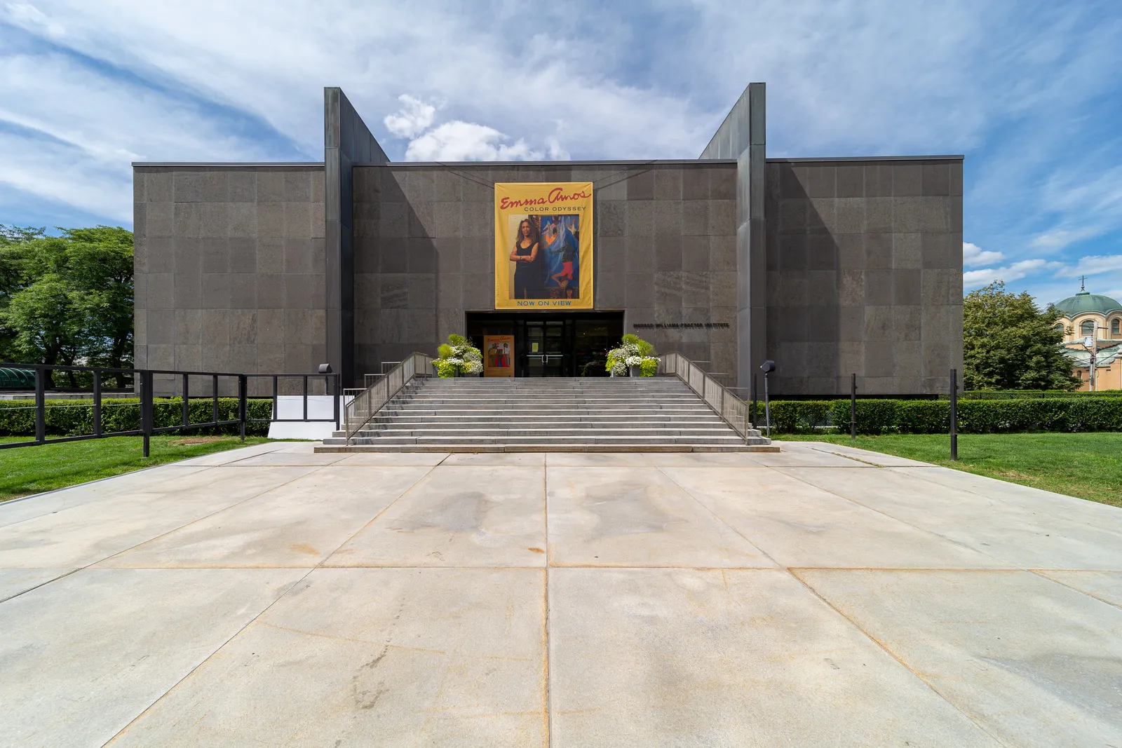 The museum building at Munson, Utica: a granite block on a raised terrace with a broad front stair and an exhibition banner over the entrance